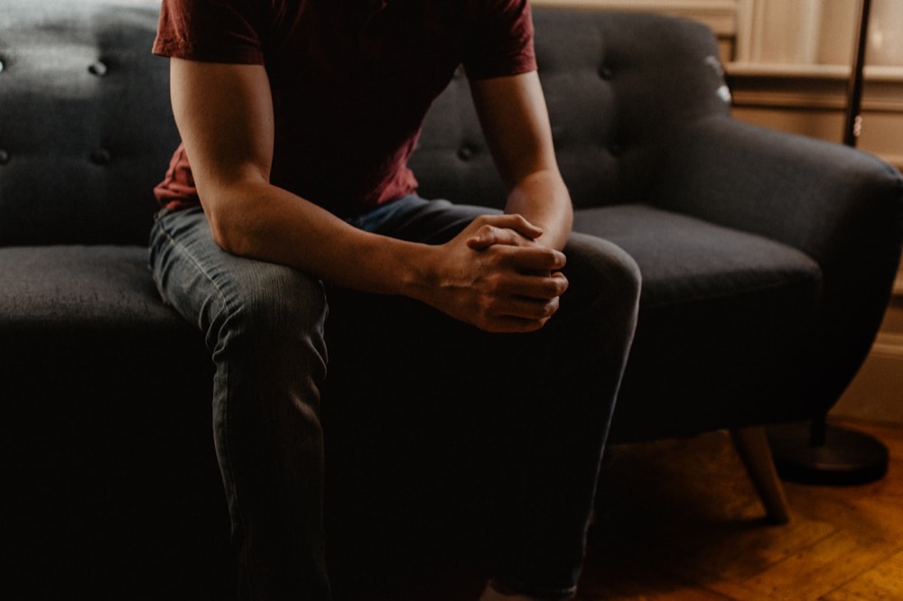 A man sitting thoughtfully on a sofa