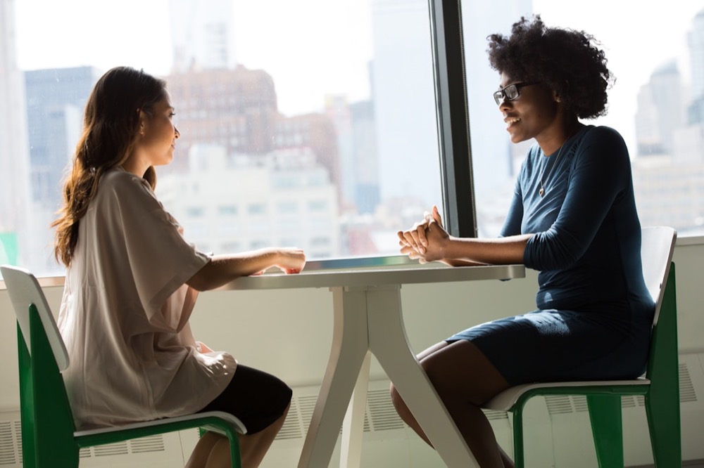 Two women sitting together in an open, supportive conversation