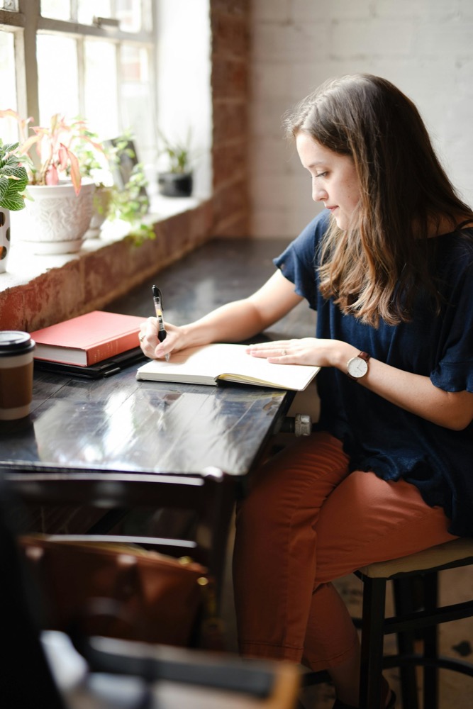 A woman journaling by a sunlit window