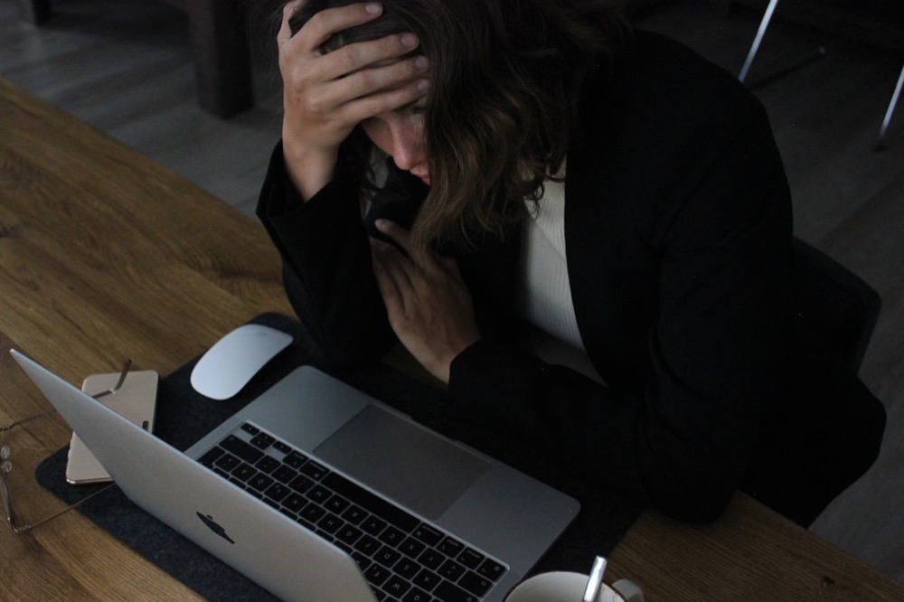 A woman looking stressed while working at her laptop