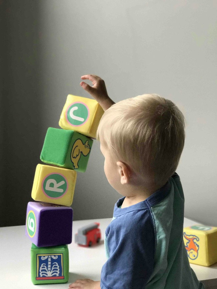 A young boy playing with building blocks at a table