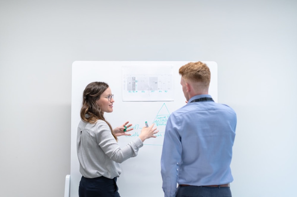 Two colleagues discussing ideas together at a whiteboard