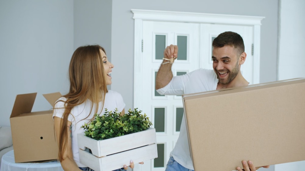 A couple happily carrying boxes into their new home
