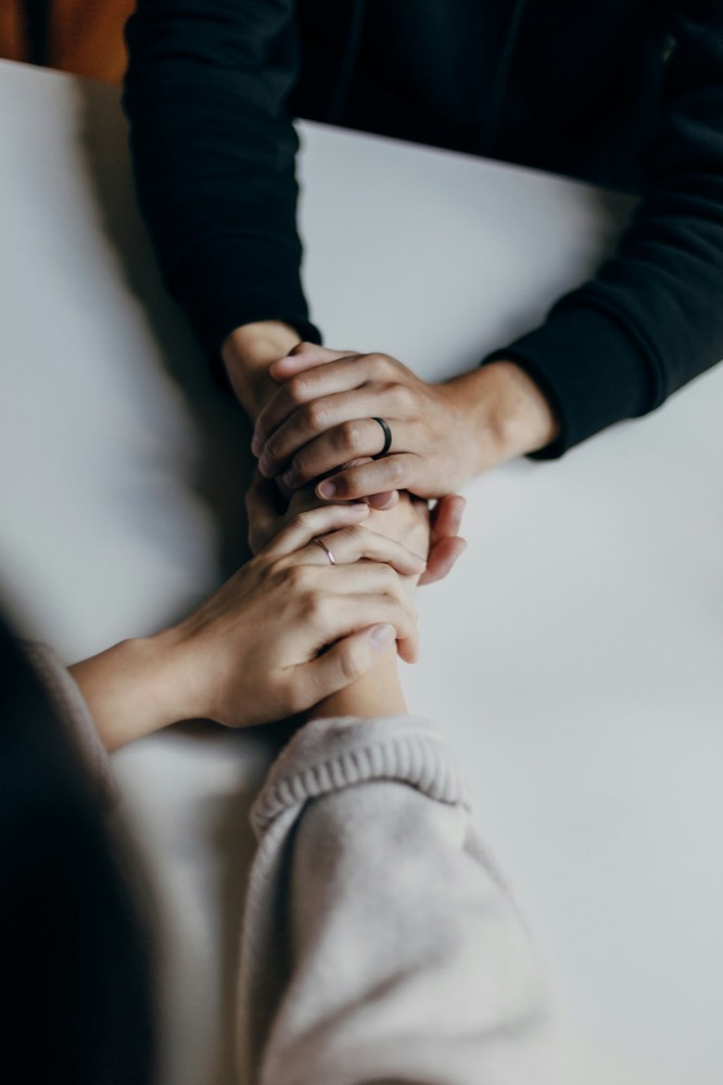 Two people holding hands in a supportive, comforting gesture