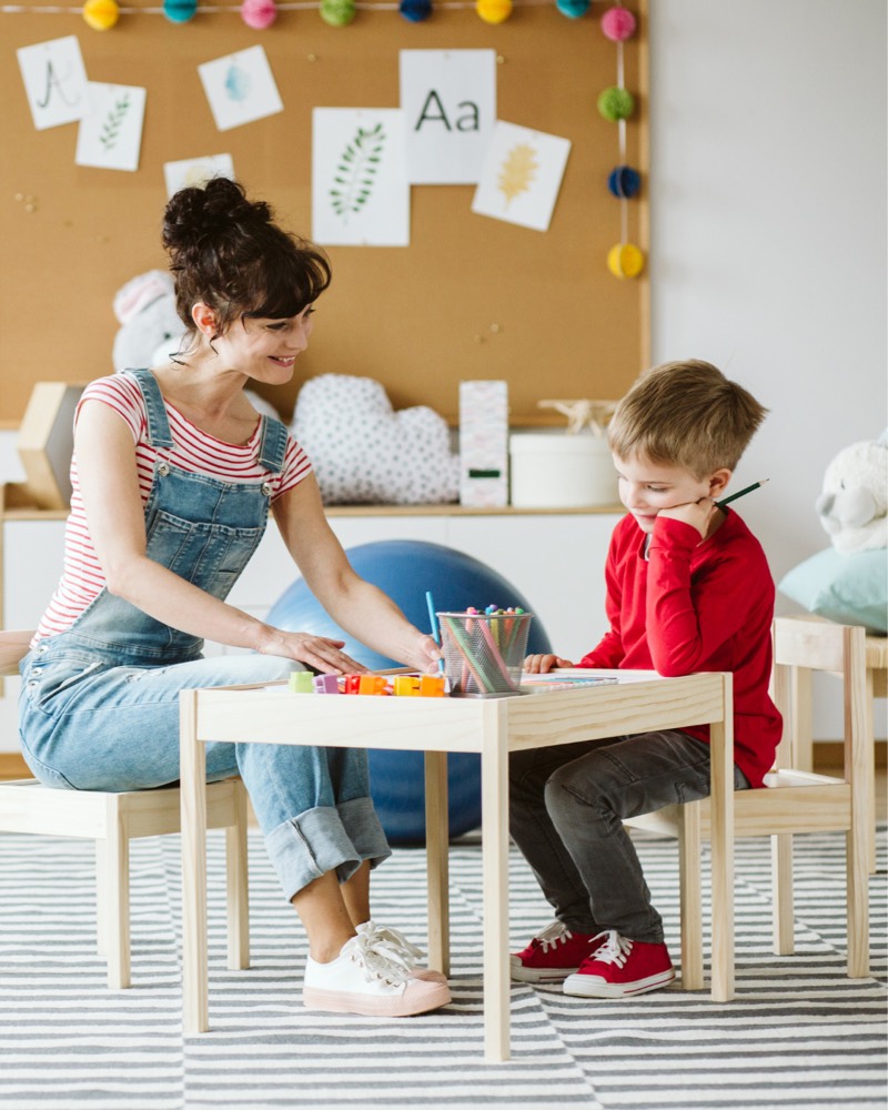 A therapist working with a young child at a play table during child therapy