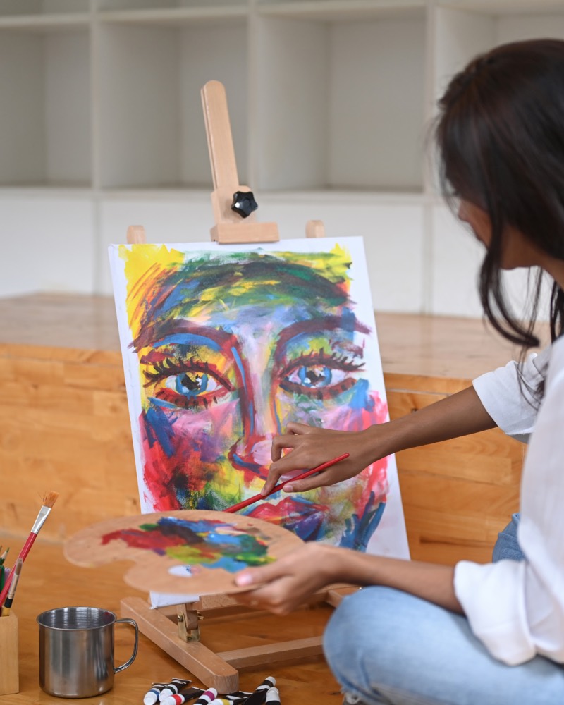 A young client painting a colorful portrait during an expressive arts therapy session